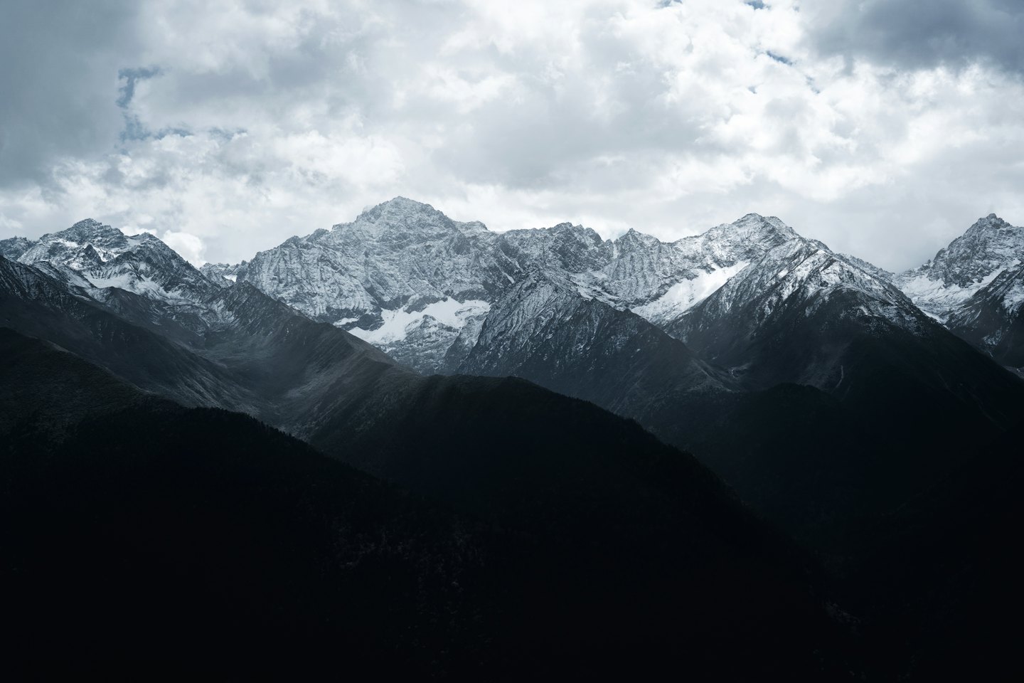 Snow-capped mountain peaks under a cloudy sky.